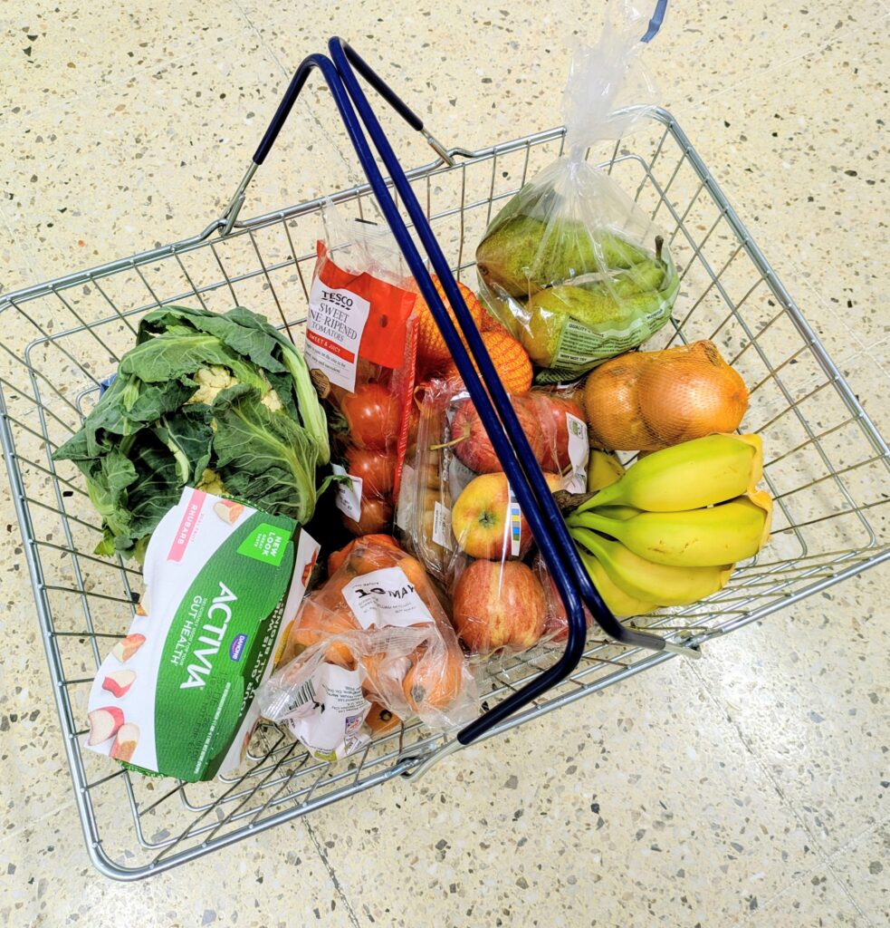 Healthy groceries including fruit, vegetables, and yoghurt in a shopping basket